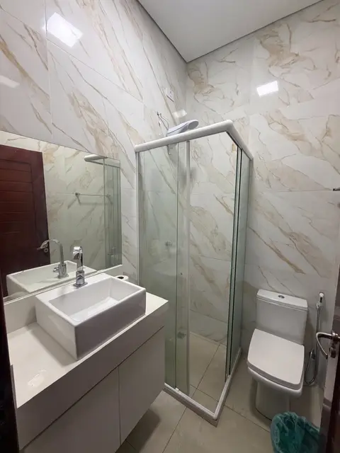 Banheiro com pia, box de vidro e vaso sanitário