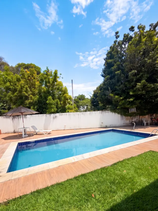 Piscina com gramado e árvores grandes em volta