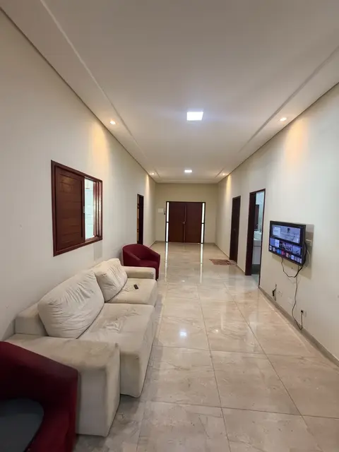 Sala de estar com sofás e televisão em um corredor largo