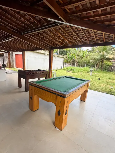 Mesa de sinuca e pebolim na área coberta, com jardim ao fundo